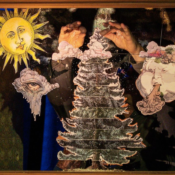 popup_gross Hände führen eine geschichtete Tannenbaum-Figur, daneben eine gemalte Sonne mit Gesicht – Figurentheater „Der Tannenbaum“